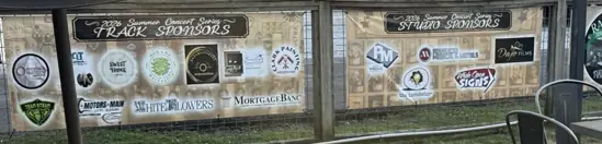 Custom event sponsor banners fitted along an outdoor venue fence for a summer concert series